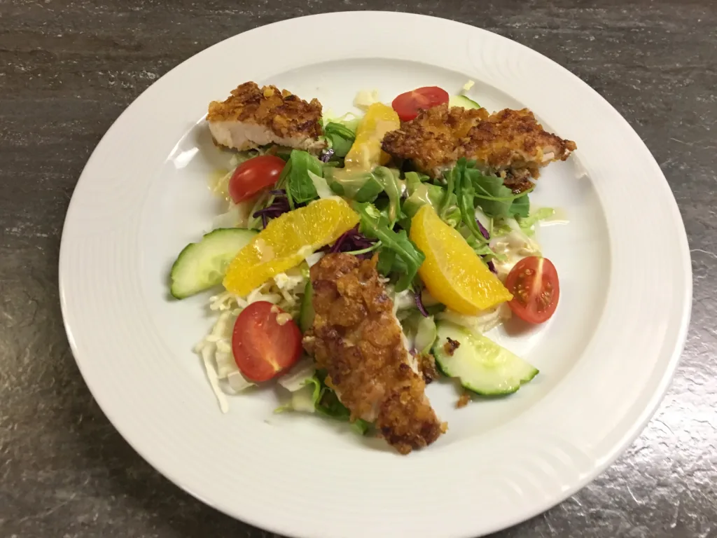 Plate of salad with crispy breaded chicken strips and orange segments
