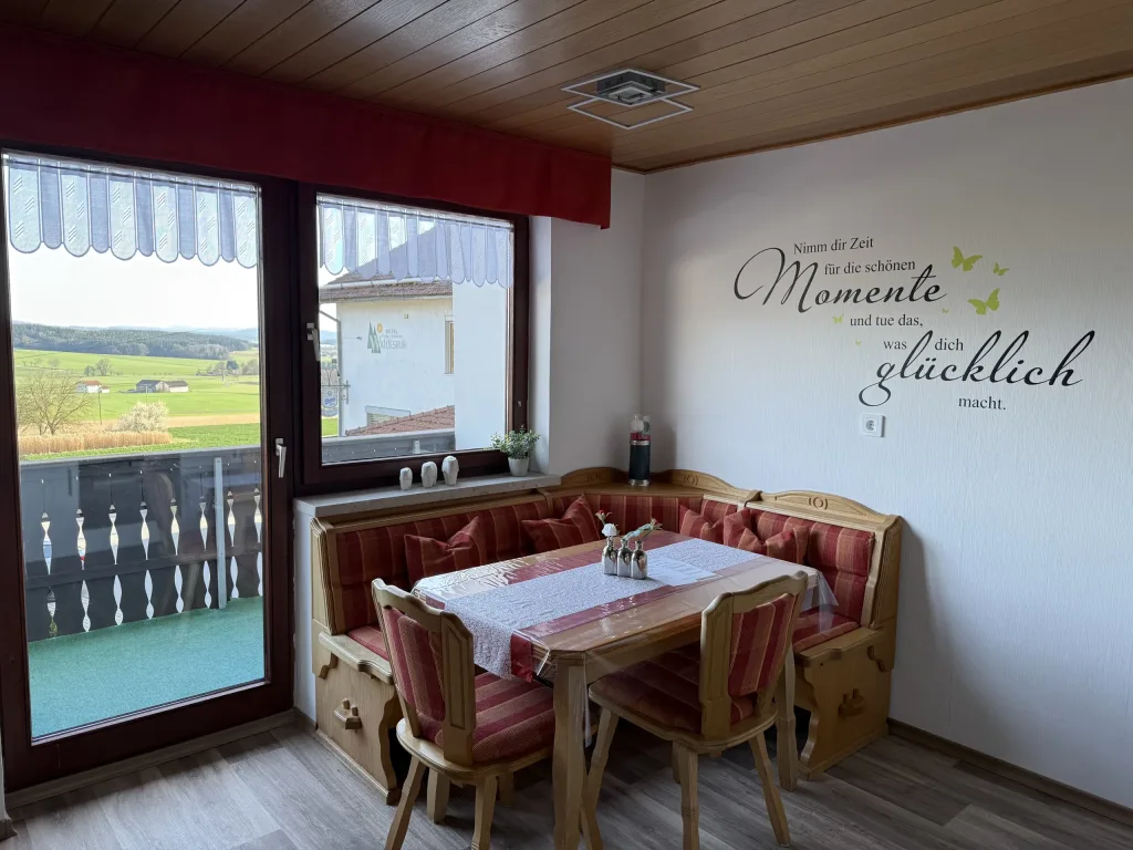 Dining corner of the holiday apartment with a corner bench and a view of the balcony