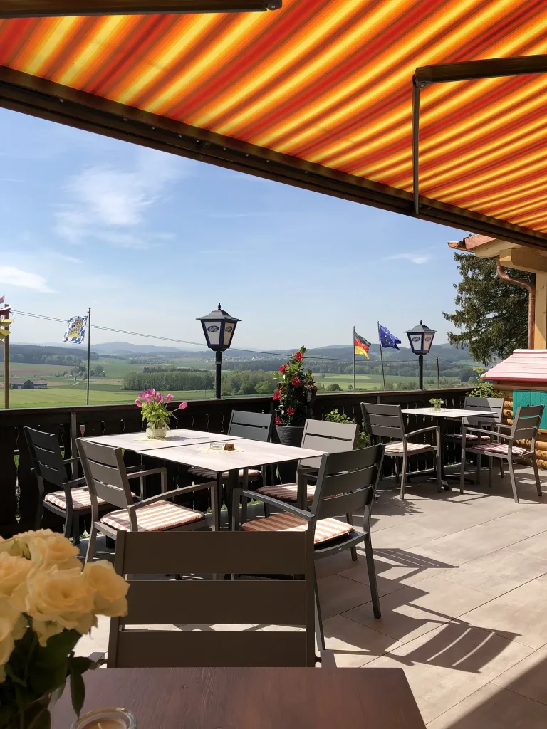 Terrace under a striped awning with a view into the valley