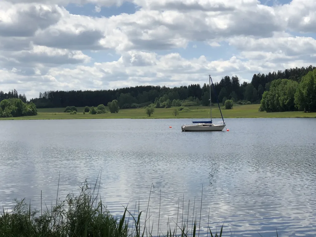 Sailing boat on a lake in front of wooded hills