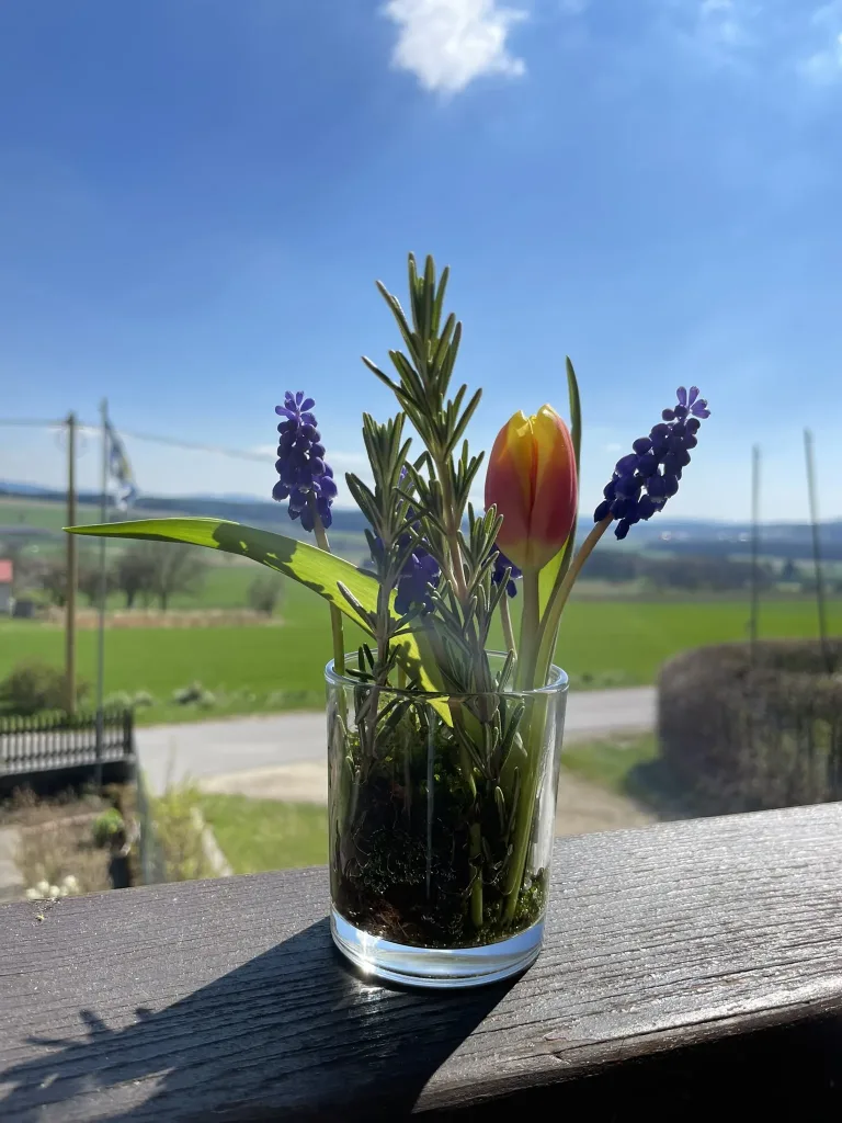 Flowers in a glass on the terrace railing with wide countryside behind