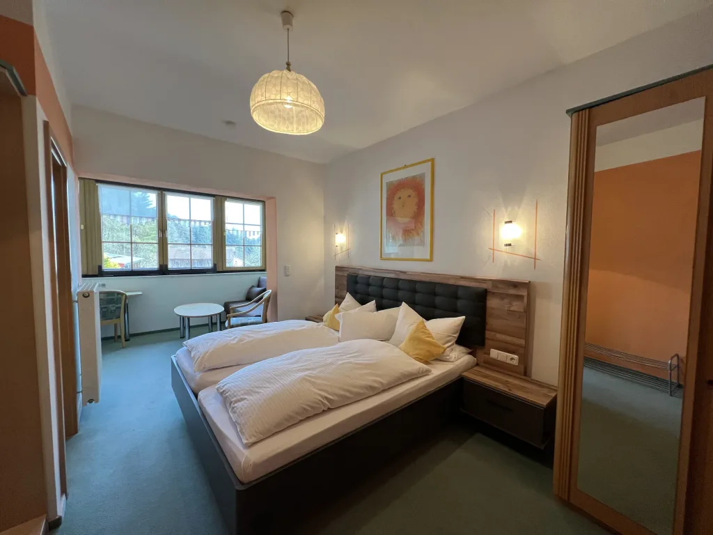 Double room with a wooden bed and a seating area by the window