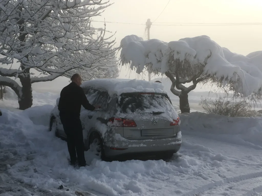 Snowed-in car being cleared of snow